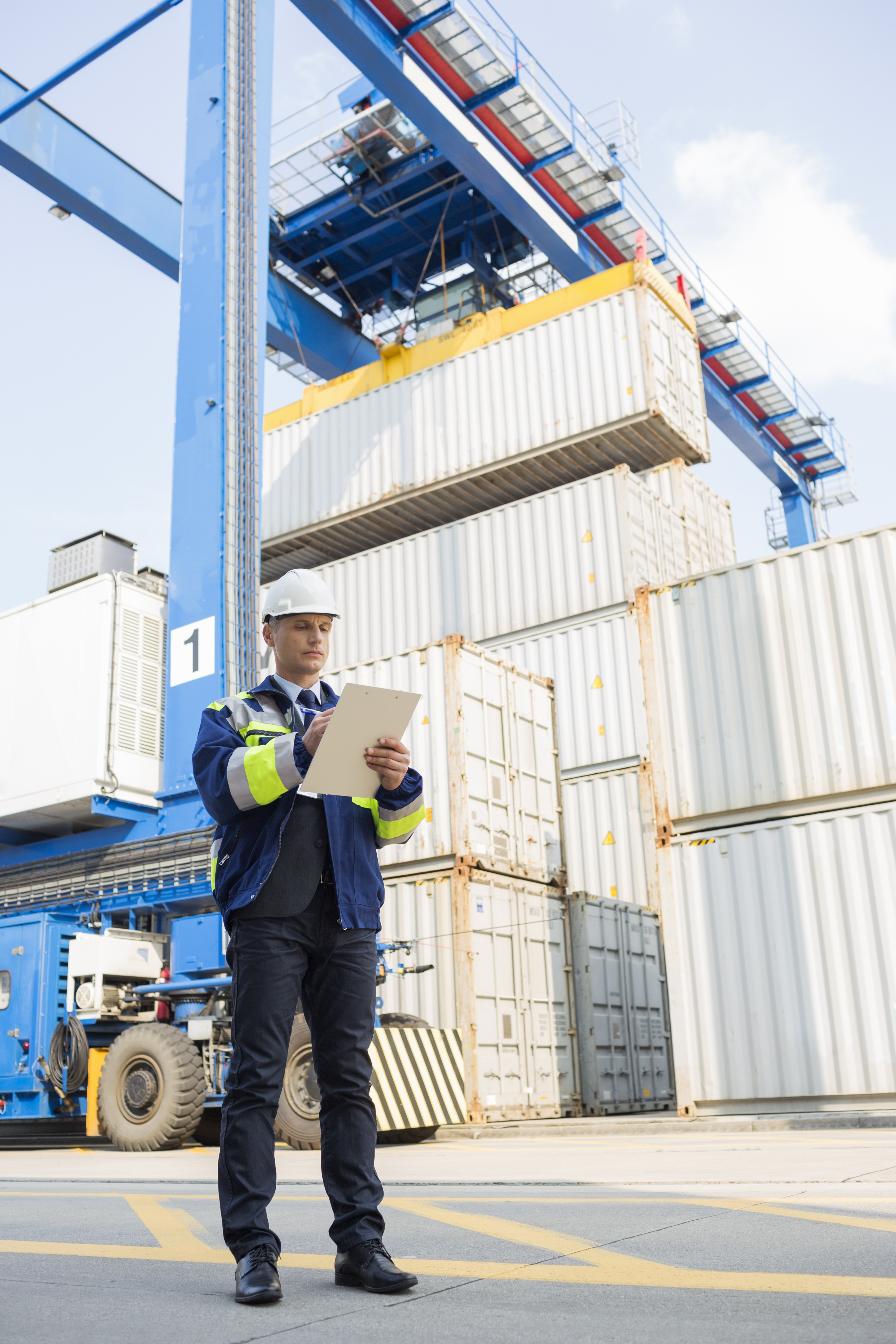 Full-length ng lalaking superbisor na nagsusulat sa clipboard sa shipping yard